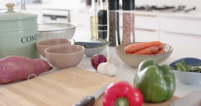 Countertop holding vegetables while camera panning right toward baking sheet with cubed squash