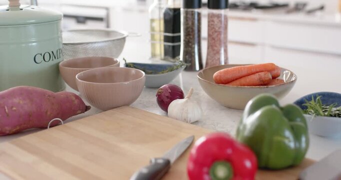 Camera gliding across bright kitchen countertop revealing cutting board, bell peppers and knife