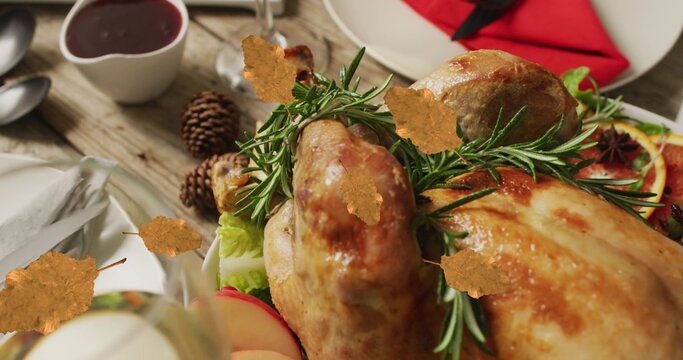 Whole roasted bird resting on rustic wooden table near red napkin, sauce bowl and pinecones