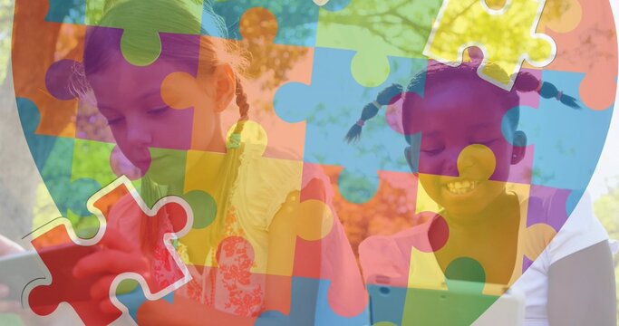 Two girls placing large red puzzle piece behind colorful puzzle overlay covering leafy trees