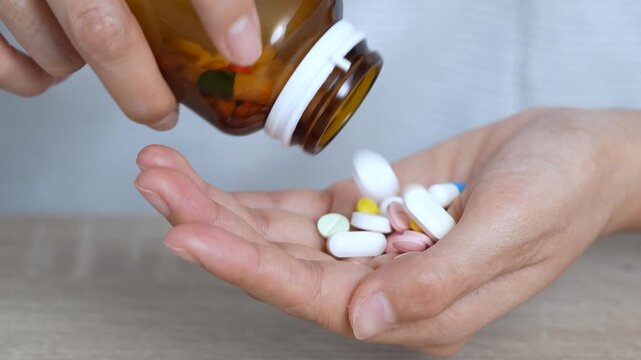 close up woman hand holding a medicine, with pours the pills out of medicine bottle. Stop drug use Taking Medication Caring for the health care medical concept.