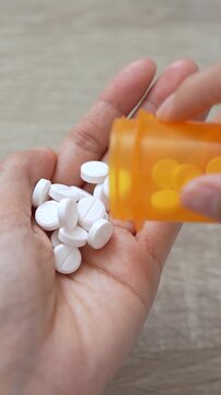 close up woman hand holding a medicine, with pours the pills out of the yellow orange medicine bottle. Stop drug use Taking Medication Caring for the health care medical concept.