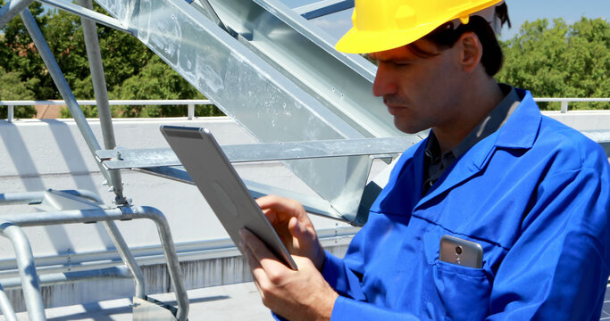 Engineer in blue uniform examines a tablet at a construction site
