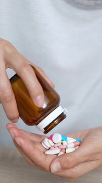 close up woman hand holding a medicine, with pours the pills out of medicine bottle. Stop drug use Taking Medication Caring for the health care medical concept.
