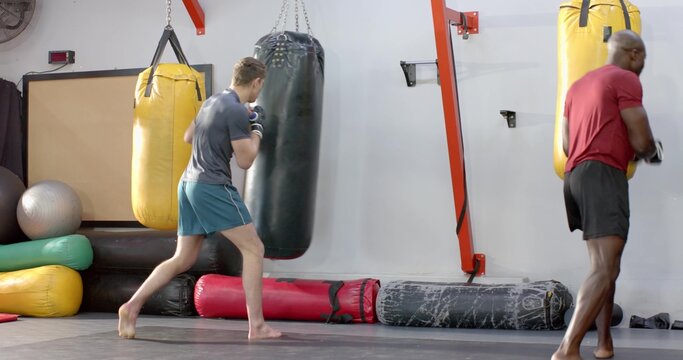 Diverse male fighters performing bag work, African American exiting as White athlete doing combos