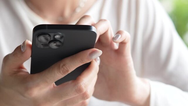 woman holds smart phone in her hands and scrolls through the news feed. Close up of hand uses mobile. point finger on screen, texting text message.