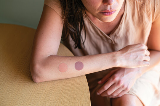 A close-up of a woman's arm showcasing two color swatches, blending the natural skin tone with a pastel hue, representing the beauty of diversity in cosmetics.