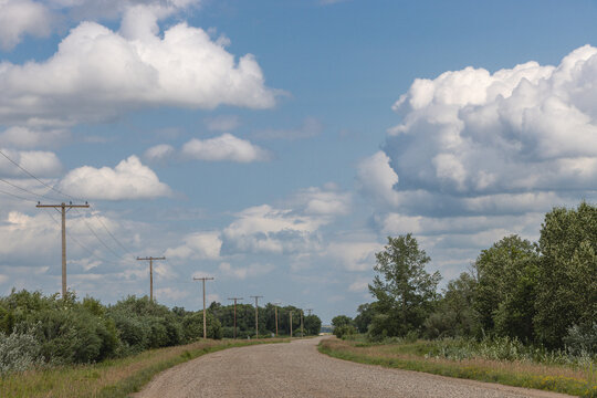 Prairie Roadside with Wooden Utility Poles and Towering Clouds in Rural Saskatchewan, Canada