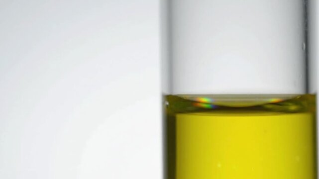 Macro shot of golden green renewable biodiesel meniscus in laboratory glassware, pristine white copy space for ESG and clean energy corporate presentation.