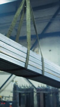 Heavy Metal Beams Being Carefully Positioned by Worker in Industrial Workshop with Visible Equipment and Equipment for Metal Processing and Handling