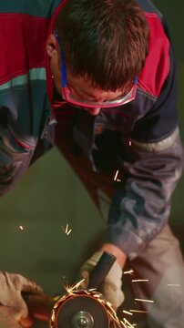 Craftsman in Action: A Skilled Worker Using a Tool to Shape Metal While Sparks Fly in a Workshop, Demonstrating Precision and Expertise in Metalworking.