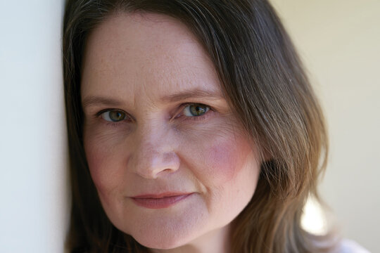 An intimate close-up portrait of a woman with long brown hair reflecting deep thoughts, combining elegance with an air of mystery in her expression.