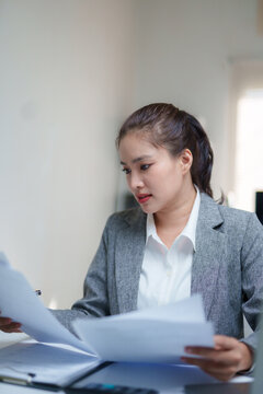 Businesswoman reviewing paperwork at her desk, comparing printed documents while managing administrative tasks in a professional office