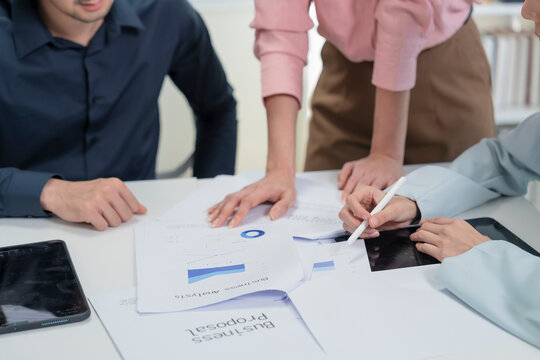 Close up of business team hands reviewing business proposal and business analysis documents with stylus and digital tablets on office table during meeting