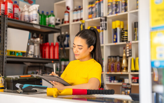 Retail latina worker, surrounded by stocked shelves, recording store inventory on a tablet