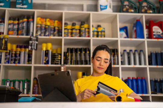 Retail worker inspecting an air filter while managing stock at an auto parts counter