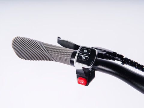 Close-up of electric scooter handlebar with ON OFF switch and horn button, isolated white background