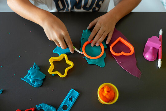 Child Pressing Shape Cutter Into Play Dough