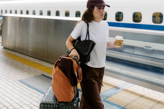 Tourist with suitcases and coffee on platform boarding the Shinkansen