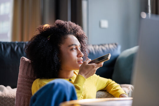 Relaxed woman rests in the living room and speaks via her phone