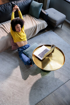Woman relaxes in the living room with a laptop in front of her.