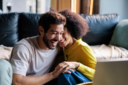 Couple laughs as they watch a movie at home