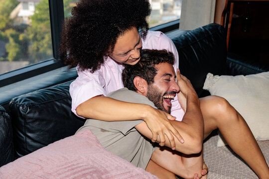 A man and a woman engage in a pillow fight at home.