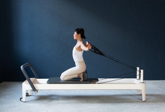 Woman Performing Backbend Stretch with Yoga Wheel on Pilates Reformer