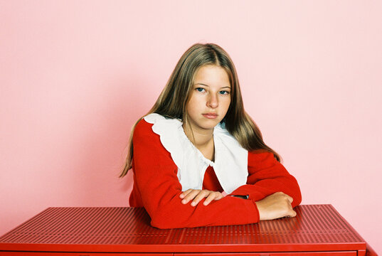 Young girl sitting at red table