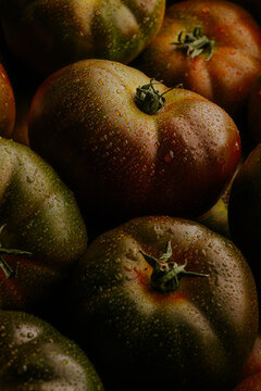 Close-up of heirloom tomato with water droplets in dark