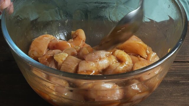 Chicken fillet marinated in teriyaki sauce with spices and garlic in a glass bowl. Close-up.