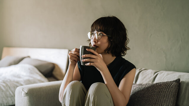 ソファに座って飲み物を飲む女性