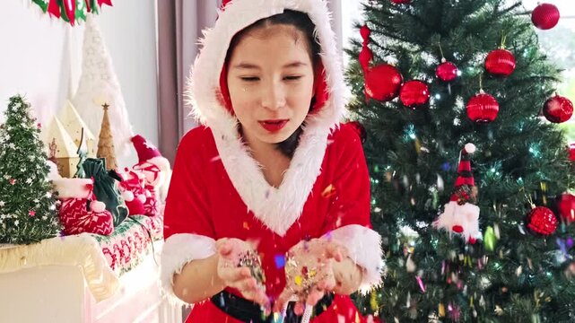 Smiling girl in a Santa outfit celebrates beside a decorated tree