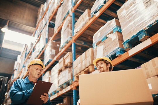 Warehouse workers checking inventory and carrying a box