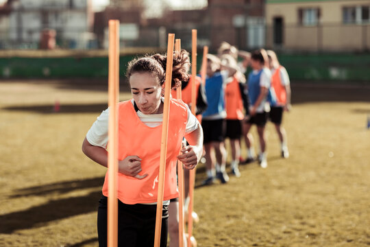 Young athlete weaving through agility poles at practice