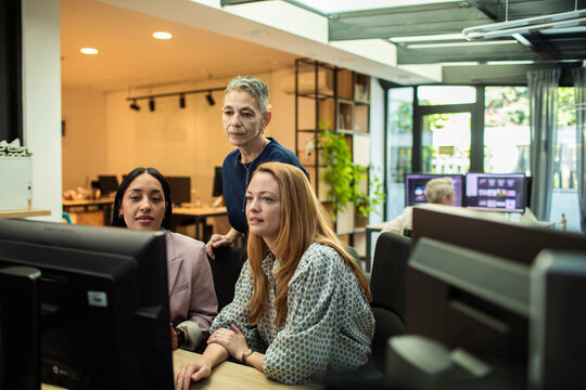 Three women reviewing project on computer in office