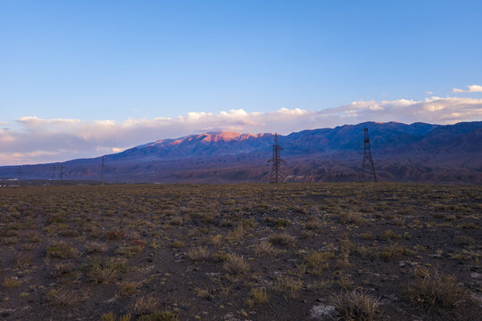 Power Transmission Towers in Arid Mountain Landscape at Sunrise or Sunset