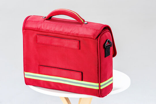   Red emergency first aid bag with reflective stripe on white background, medical rescue kit