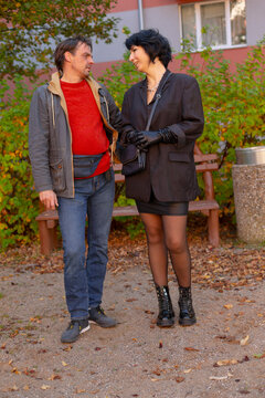 Man and woman standing together near bench in autumn park setting