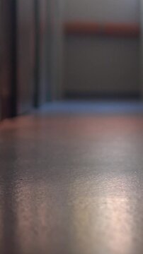 Low-angle polished floor reflection in empty indoor corridor with soft