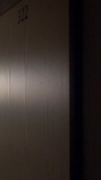Dim narrow corridor with numbered doors and warm side lighting casting