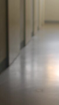 Empty school corridor with closed classroom doors and bright window at