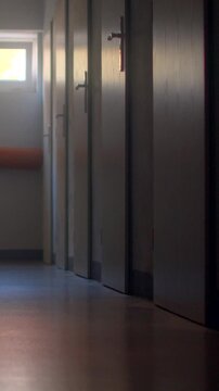 Empty school corridor with row of classroom doors and soft daylight in