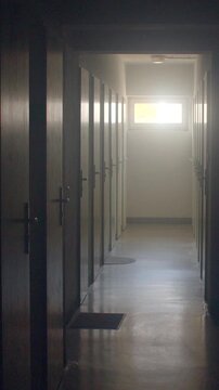 Narrow school corridor with rows of closed classroom doors leading to