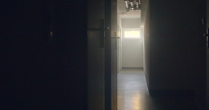 Empty school corridor with open classroom doors and window light atfar