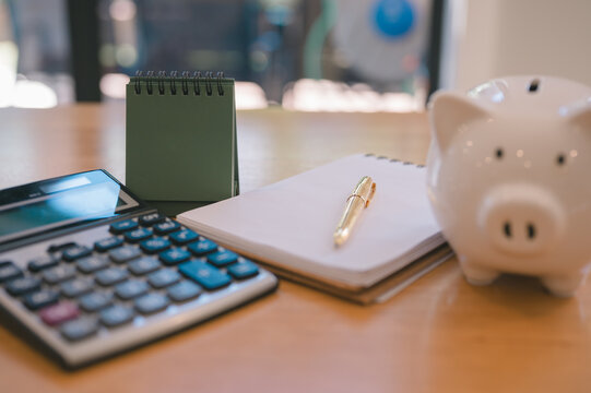 Empty calendar piggybank and notebook with pen and calculator machine on wood table in concept of business planning or personal financial planning.