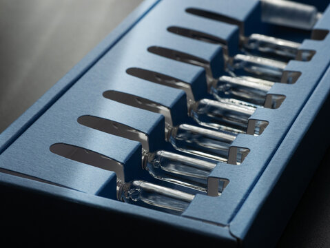 Glass Skincare Serum Ampoules in Blue Packaging on Dark Background