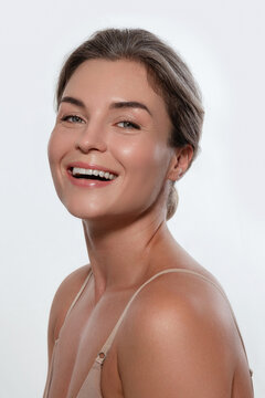 Beauty portrait of a smiling woman with radiant skin, subtle makeup posing against a white background