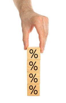 Discount concept. Man stacking wooden cubes with percent signs against white background, closeup