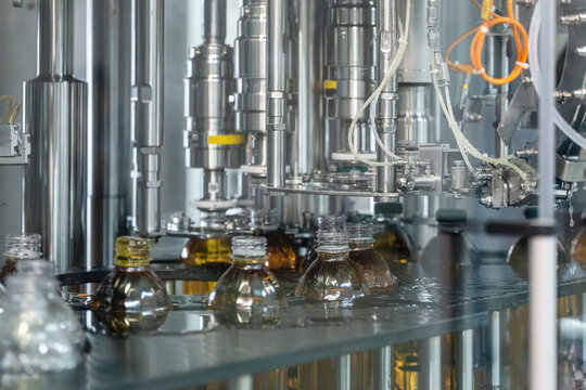Automated Beverage Bottling and Liquid Filling Machine Dispensing Amber Drink into Plastic Bottles on Industrial Production Line, Factory Manufacturing Equipment.